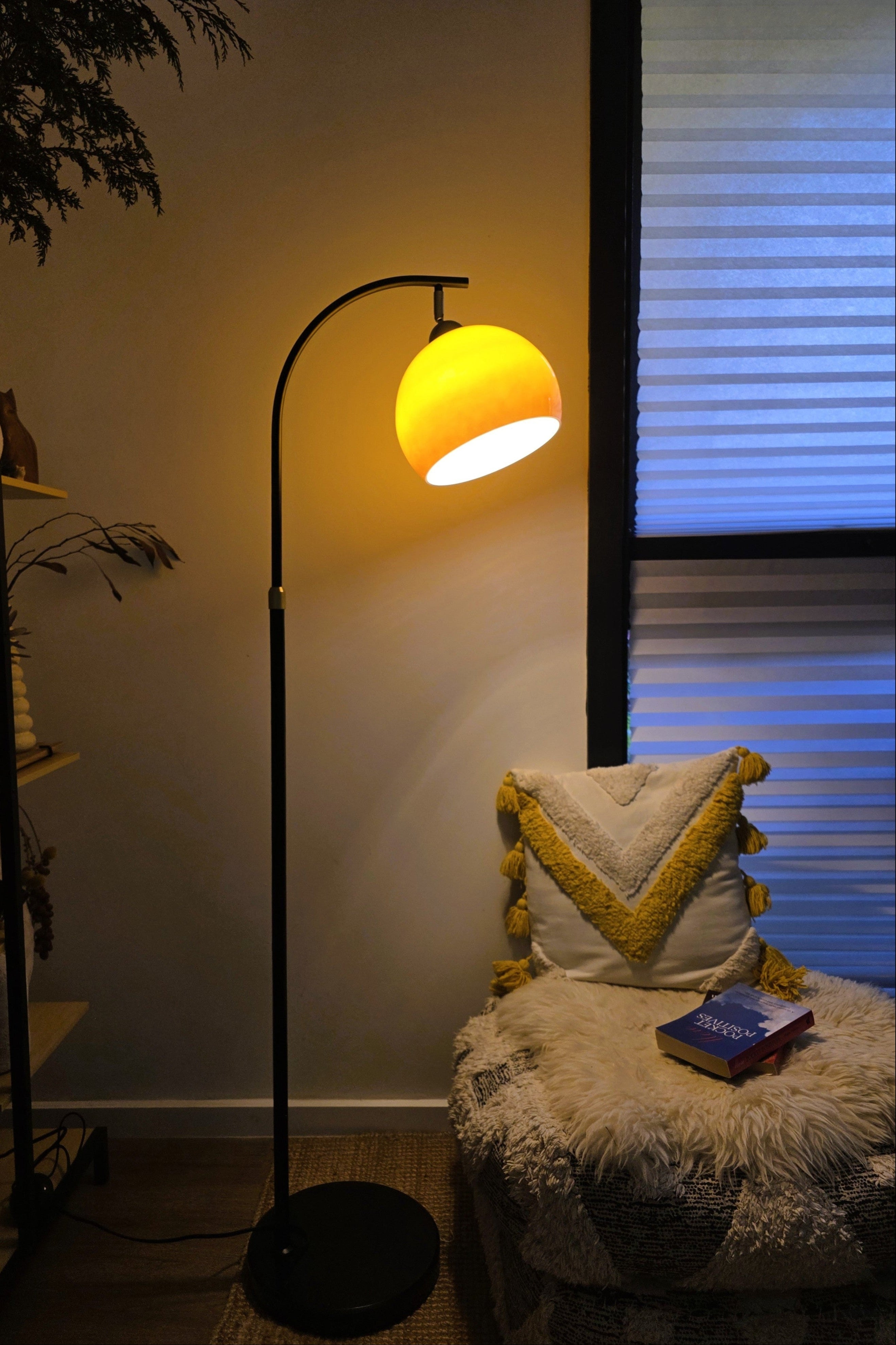 Mushroom  Bella Arc Floor lamp with a Glass Yellow Orange Gradient shade in a dimly lit room.