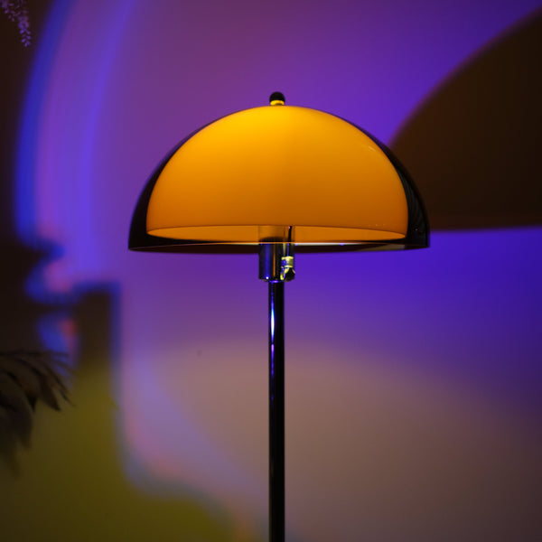 Retro 70s inspired orange mushroom floor lamp casting warm ambient glow Yellow lampshade on a dark background