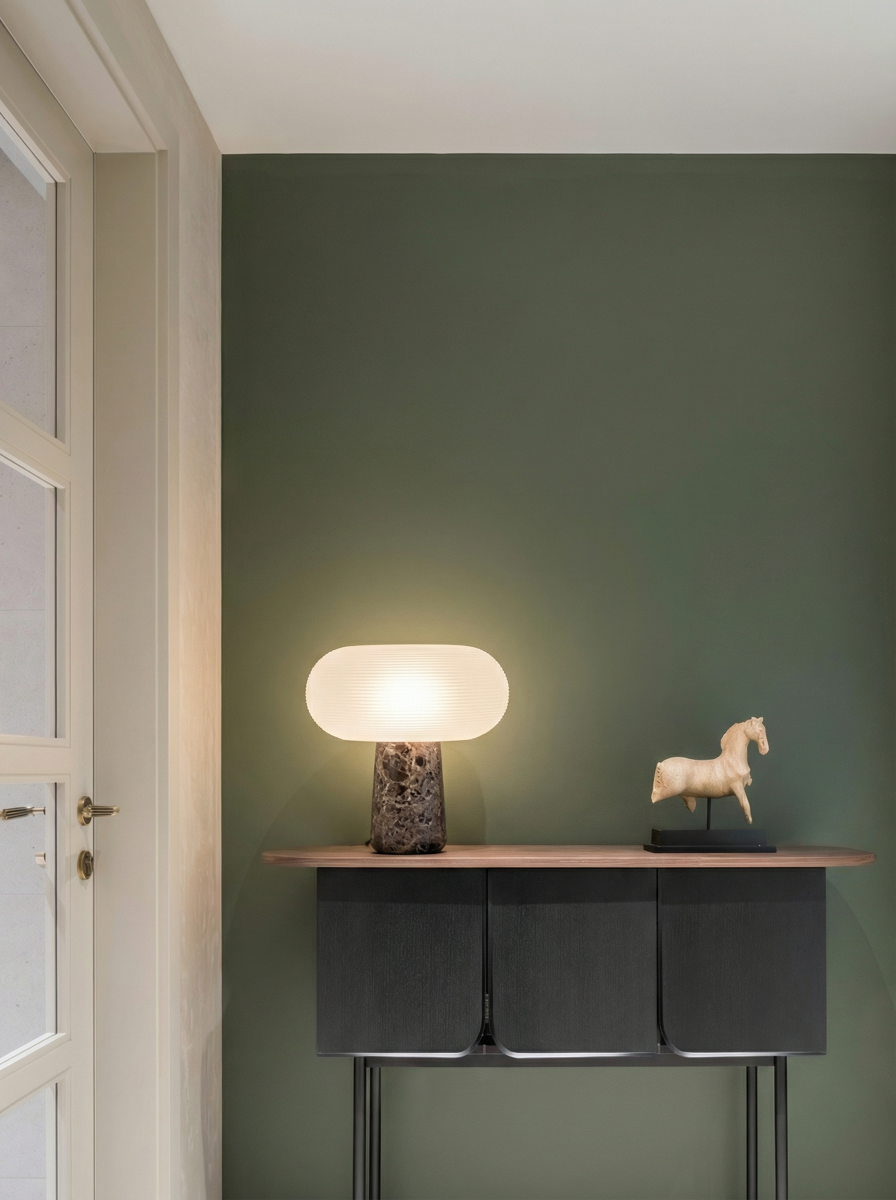 Modern table lamp on a sideboard against a green wall