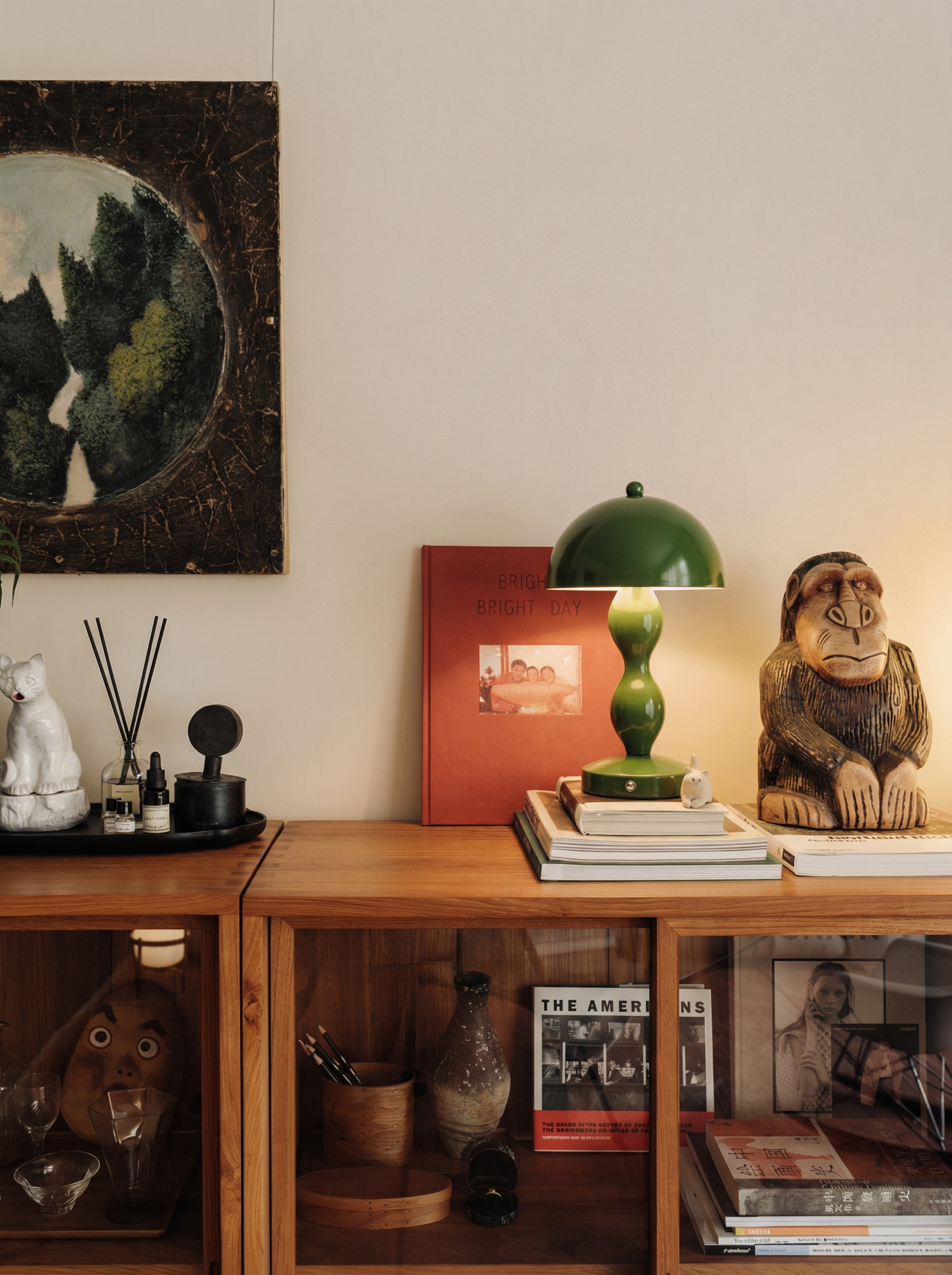 Wooden shelf with decorative items including a green lamp, books, and a monkey figurine.