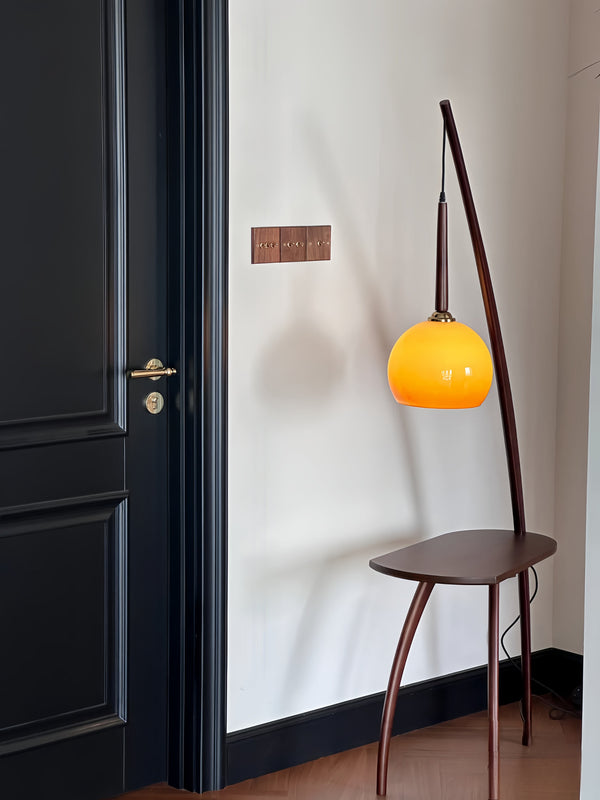 Yellow Domus Pollo Floor Lamp Curve Leg  next to a black door with a gold handle.