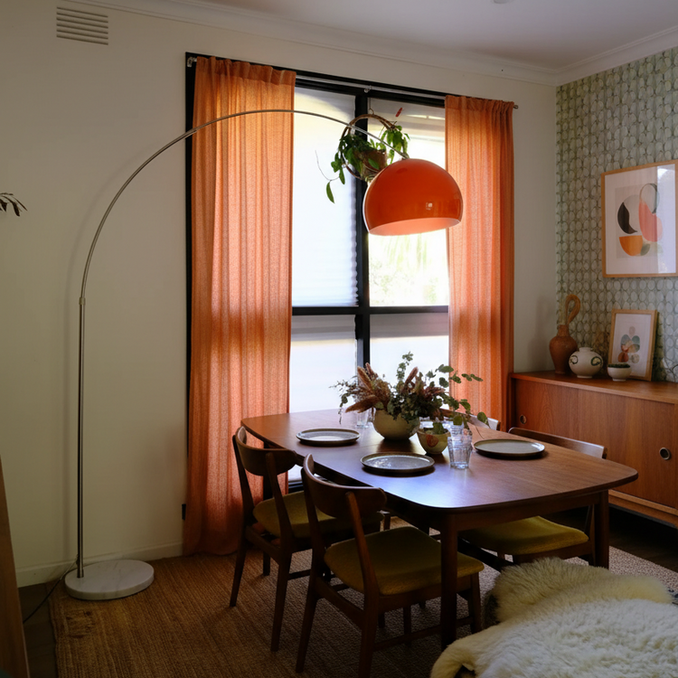 Dining room with wooden table, chairs, and a lamp with an orange shade.
