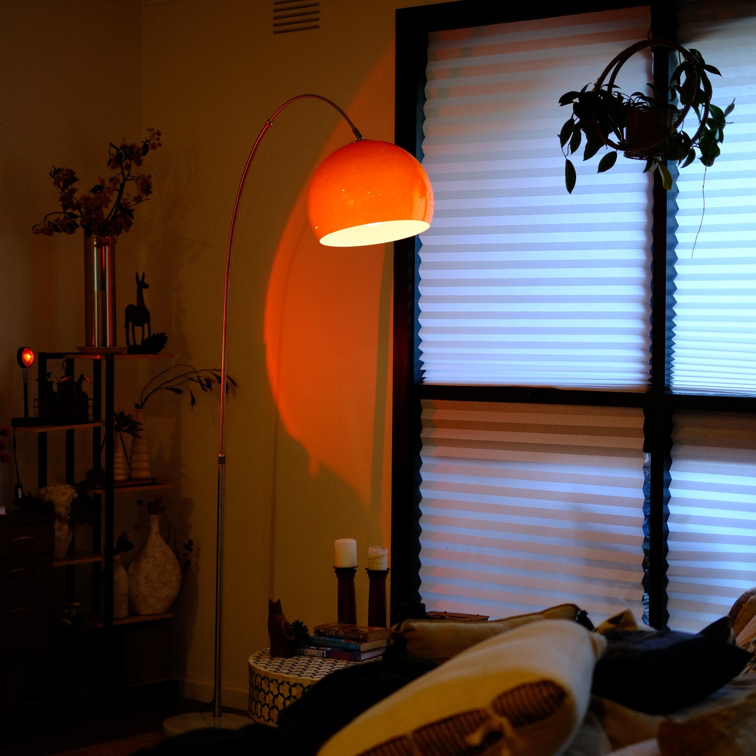 Sneedville+ Bauhaus Arc Floor Lamp with chrome arc and marble base in white shade Orange lamp casting a warm glow in a dimly lit room with posters and decor. Living room with a floor lamp casting an orange glow, a window with blinds, and decorative items.