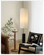 Floor lamp with pleated white fabric shade and black metal post