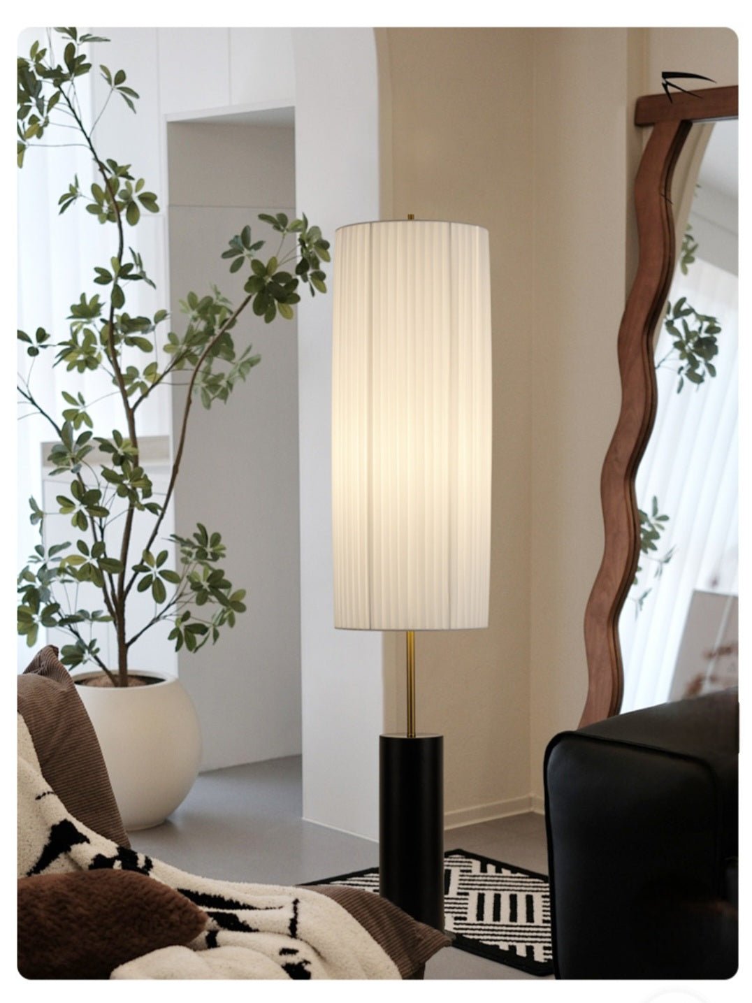 Floor lamp with pleated white fabric shade and black cylindrical base