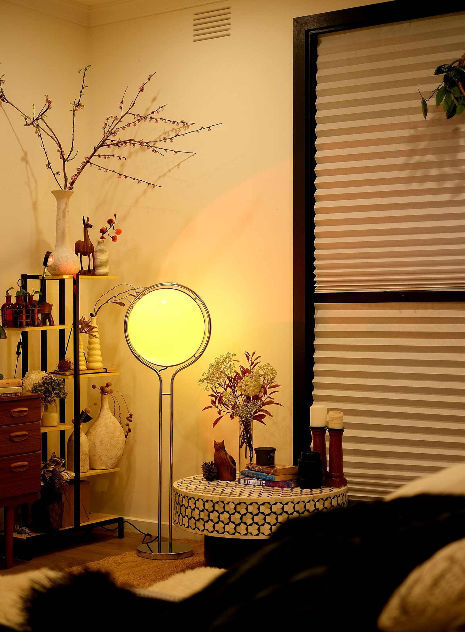 Living room with a floor lamp, decorative items, and a window with blinds.